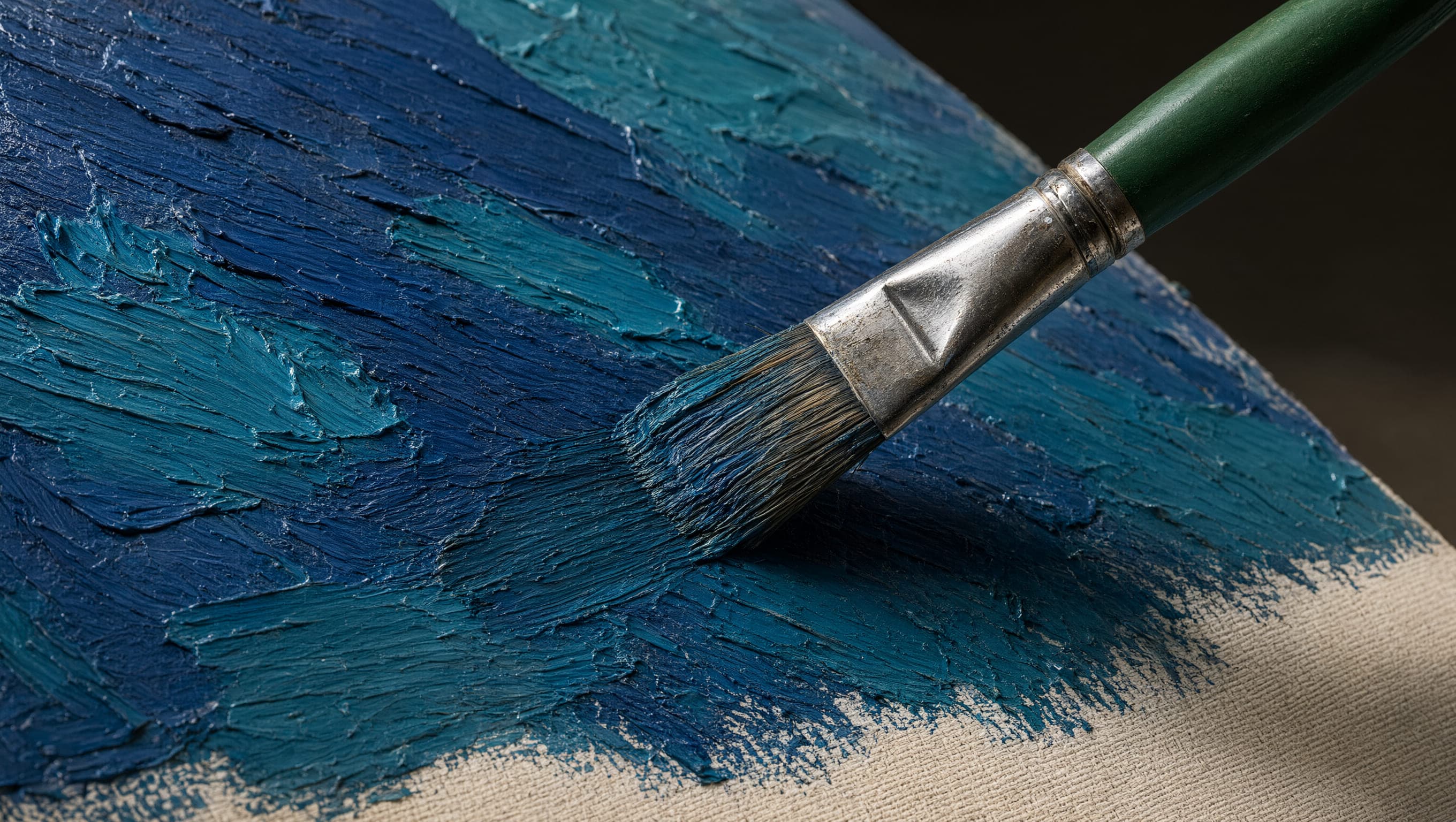 Paintbrush applying thick blue paint across a textured canvas